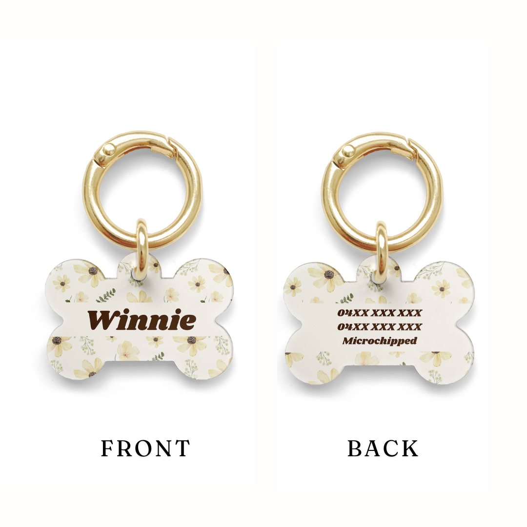 Example of where the contact details would sit on a pet ID tag with a floral sunflower design, bone shaped with a gold ring.