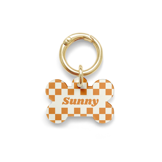 Orange and white checker styled Pet ID tag in a bone shape with a gold ring. 