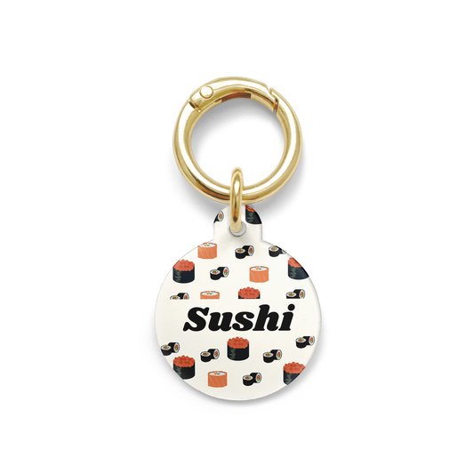 Circle shaped pet ID tag with a design showing various types of sushi with gold ring.
